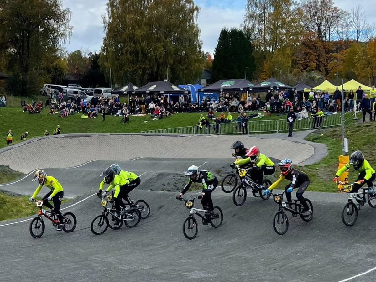 Barn i BOC-drakt sykler i en sving på BMX-banen mens publikum ser på